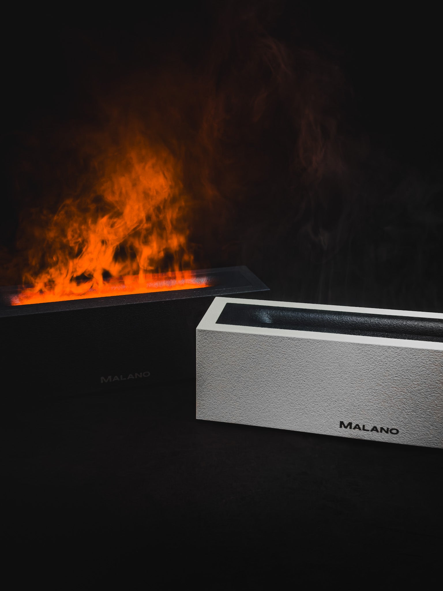 Malano Flame Aroma Diffuser & Humidifiers on display against a dark background. The matte black displaying bright orange lit steam looking like flames in the background and the white in front with steam and no light.