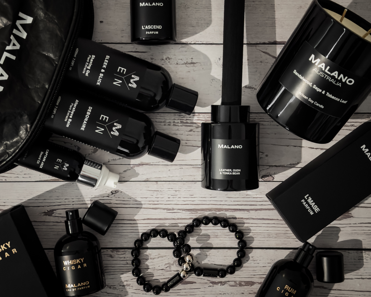 Collection of Malano products tailored for Father’s Day from candles, reed diffusers, jewellery, perfumes and mens grooming products on a wooden surface
