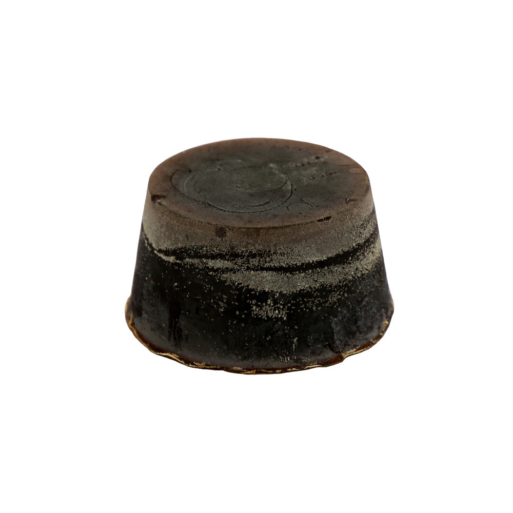 A dark-colored round hypoallergenic organic soap block.