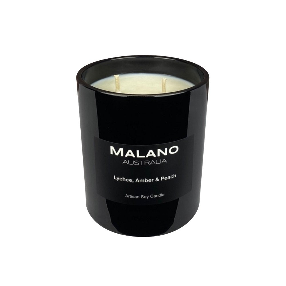 A black glass jar containing a hand poures scented soy wax candle with multiple wicks, labeled 'MALANO’ with the fruity scent of Lychee, Amber & Peach, set against a white background.