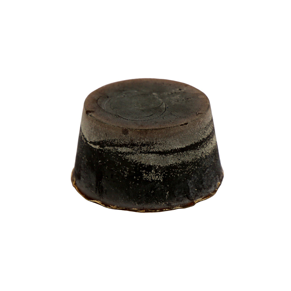 A round block of Pineapple, Coconut and Vanilla scented soap, with a dark brown colour and a textured surface.