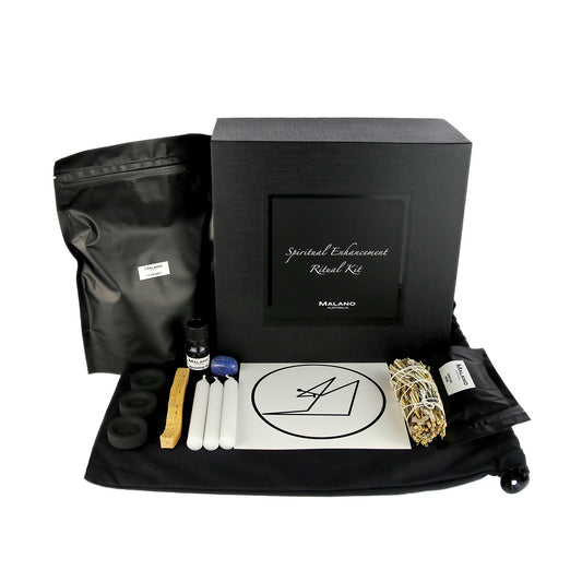 A Spiritual Enhancement Positive Intention Ritual Kit by Malano with it’s box and contents layed out in a tidy and organised manner including a bag of White Rock  Salt, Anointing Oil, Charcoal, a stick of Palo Santo, three white candles, a gem stone, Spiritual Enhancement sigil, Yerba Santa, Juniper and Sage smudge stick and Spiritual Enhancement Resin. These elements are sitting ontop of a black drawstring bag and against a white background.