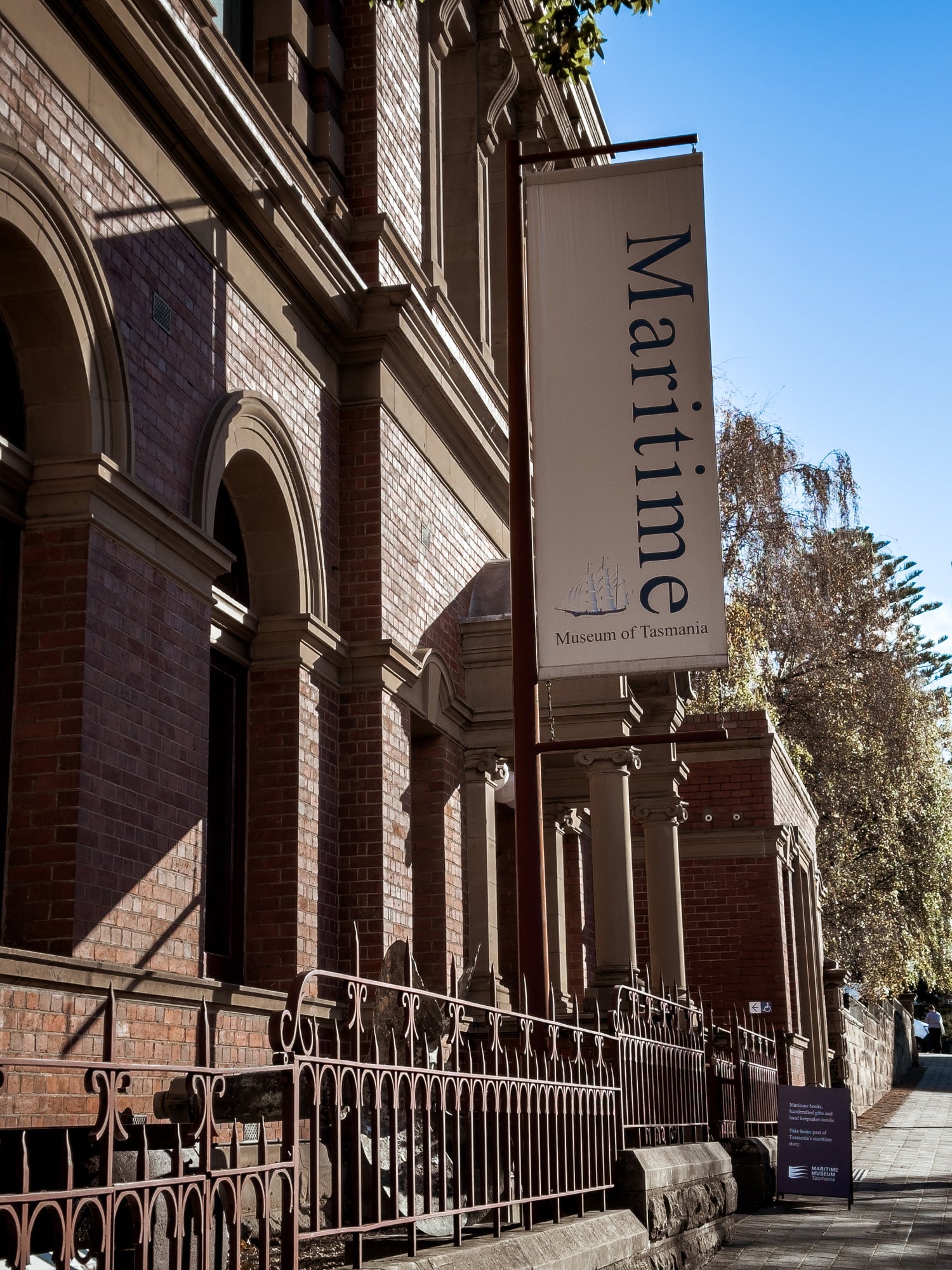 Brick and sandstone building with a 'Maritime Museum Tasmania' sign on a clear day out the front of the building