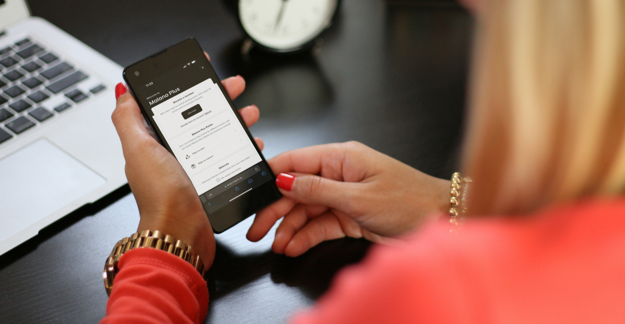 Lady holding phone displaying the Malano Plus Loyalty Rewards program