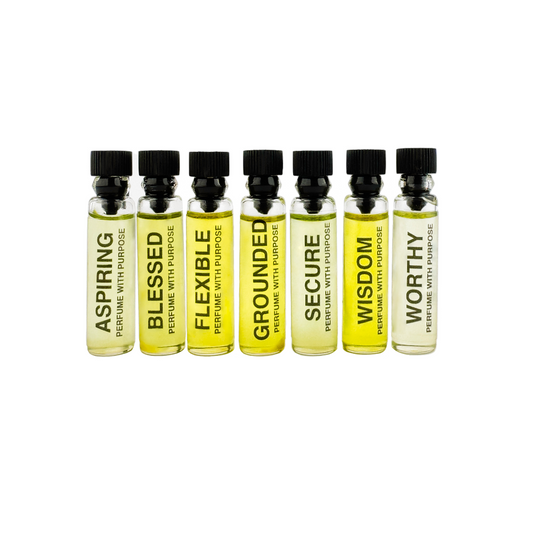 A series of seven small, clear glass sample bottles labeled with Perfume With Purpose and the names 'Aspiring', 'Blessed', 'Flexible', 'Grounded', 'Secure', 'Wisdom', and 'Worthy', each bottle containing a sample of perfume oils.