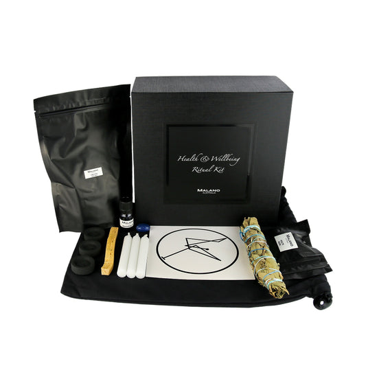 A Health and Wellbeing Positive Intention Ritual Kit by Malano with it’s box and contents layed out in a tidy and organised manner including a bag of Himalayan Pink Salt, Anointing Oil, Charcoal, a stick of Palo Santo, three white candles, a gem stone, blessing sigil, Costal Swamp Paperbark, Coastal Tea Tree and Pandanus smudge stick and Health and Wellbeing Resin. These elements are sitting ontop of a black drawstring bag and against a white background.