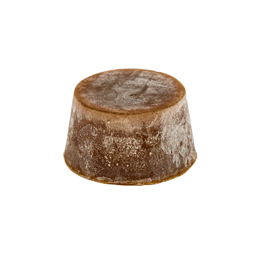 A solid organic block of coconut lime soap with a brownish color and a textured surface.