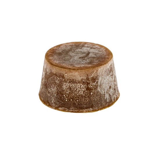 A solid organic block of coconut lime soap with a brownish color and a textured surface.