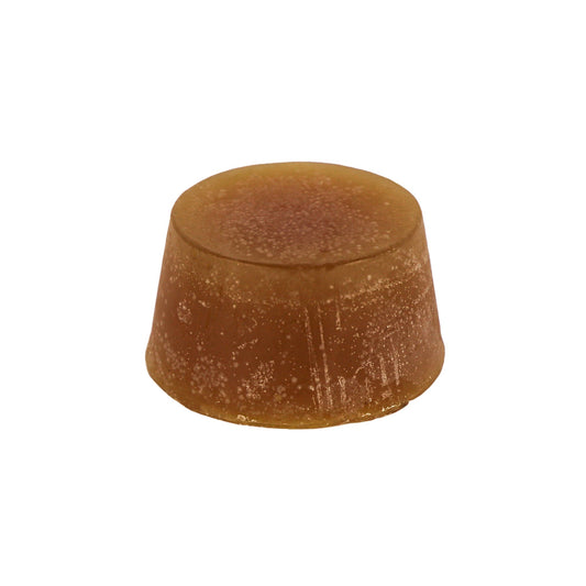 A round block of Yuzu and Patchouli scented soap, with an orange/ brown colour and a textured surface.