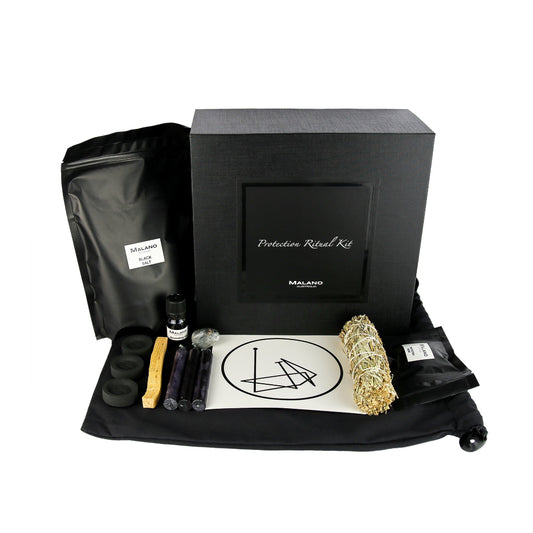 A Protection Positive Intention Ritual Kit by Malano with it’s box and contents layed out in a tidy and organised manner including a bag of Black Salt, Anointing Oil, Charcoal, a stick of Palo Santo, three black candles, a gem stone, protection  sigil, Yerba Santa, Juniper and Sage smudge stick and Protection Resin. These elements are sitting ontop of a black drawstring bag and against a white background.